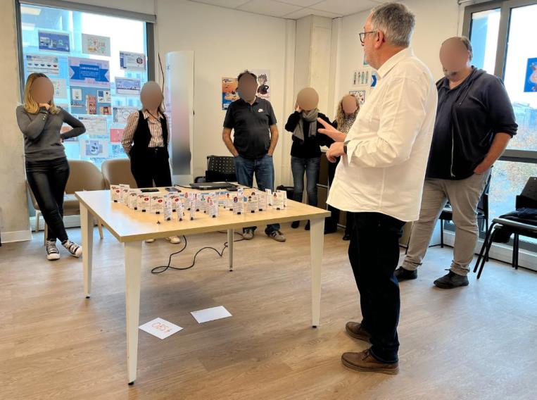 Richard et des participants autour d'une table avec jeu pédagogique